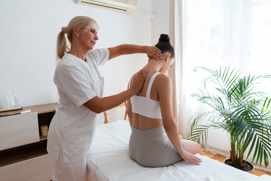 Physiotherapist treating backache of teenage patient with massage at hospital
