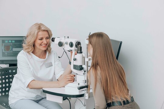 Happy ophthalmologist examining patient's eyes with slit lamp at medical clinic