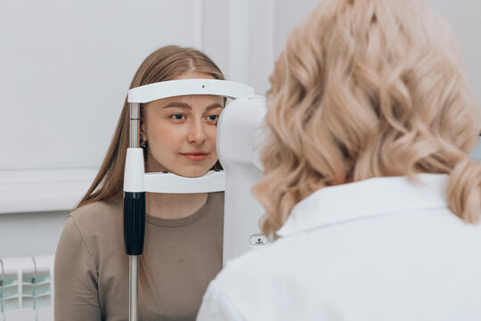 Doctor examining woman eye with slit lamp at clinic