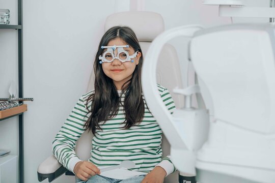 Smiling girl wearing phoropter at eye clinic
