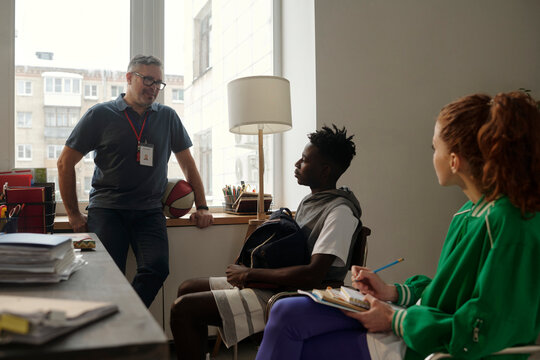 Coach giving instructions of baseball game to students in university office
