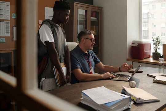 Coach discussing over online tutorial of baseball game with student