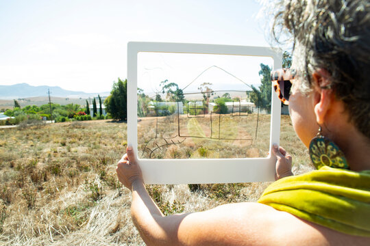 Mature woman planning house with transparent frame on sunny day