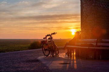 Germany, Schleswig-Holstein, St. Peter-Ording, Bicycles parked in front of Bohler lighthouse at sunset