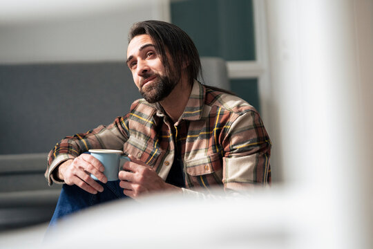 Businessman holding coffee cup and day dreaming at office