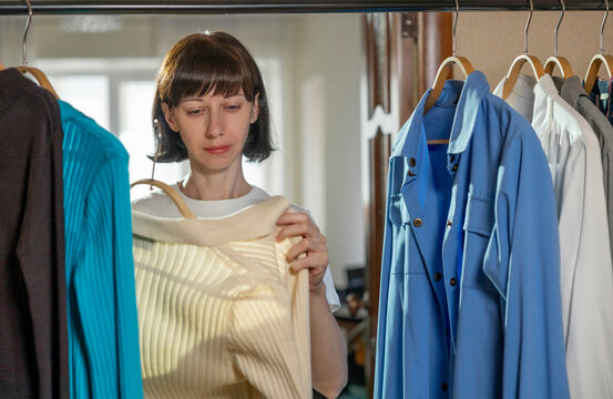 Woman hangering ironed shirt near clothes rack at home