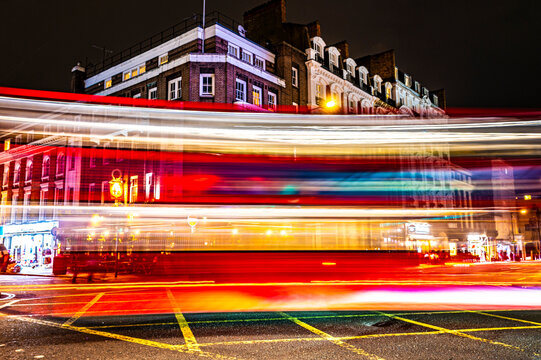 UK, England, London, Long exposure of double-decker bus driving past intersection at night