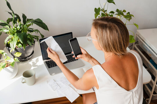 Freelancer calculating financial bills over smart phone at desk