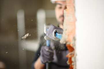 Construction worker wrecking wall using escarpment and hammer