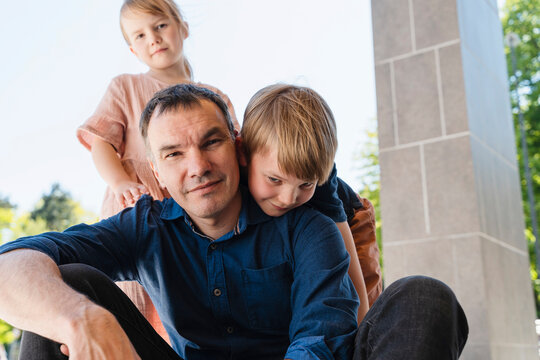 Smiling father enjoying with son and daughter near column