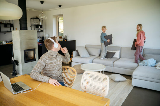Man gesturing children playing with pillow to keep quite at home