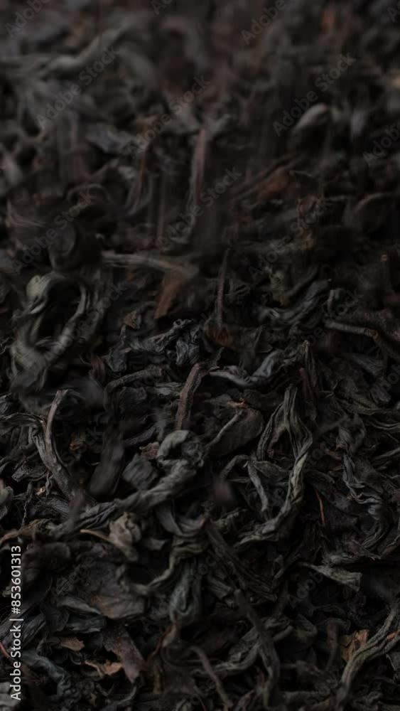 Wall mural heap of dried black tea leaves falling down in wooden bowl