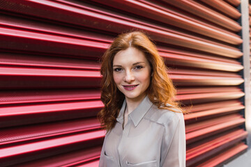 Beautiful redhead woman standing in front of corrugated iron