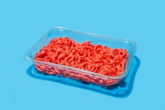 Ground beef in plastic tray against blue background