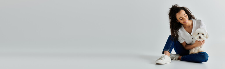 Young woman sits on floor, tenderly holding fluffy white dog.