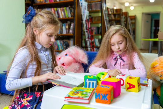 Two girls carefully read books in a children library