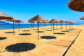 Row of wooden umbrellas at sandy beach, sea