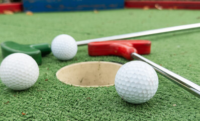 Mini golf. A club and a white ball on a golf course.
