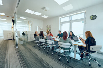 Diverse Business Team Discussing Projects in a Modern Glass Office.