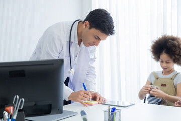 Fototapeta premium Professional collaboration child's health team and patient in hospital. Caucasian pediatrician male using stethoscope diagnosis. Family-oriented health care with senior Asian female and young doctor