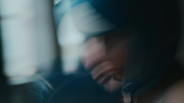 Blurred close-up with slow shutter effect of female boxer in blue padded helmet and gloves furiously pummeling punch bag in gym, while preparing for championship