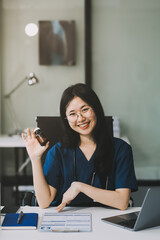 Portrait of beautiful physician doctor sit on table in office hospital. Attractive therapist female practitioner pharmacist smile and looking at camera after success work from treatment in hospital.