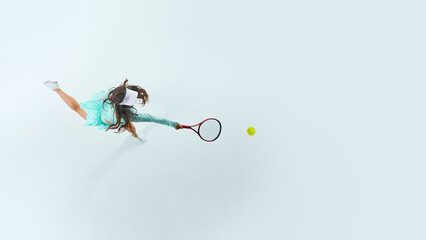 Dynamic aerial view of young, athletic female tennis player hitting forehand shot against white studio background. Concept of professional sport, championship, active lifestyle, tournament. Ad