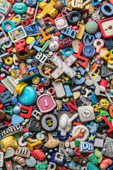 Fototapeta premium A crowded assortment of fridge magnets in various shapes, sizes, and colors, filling the entire frame. The magnets include letters, numbers, and novelty designs.