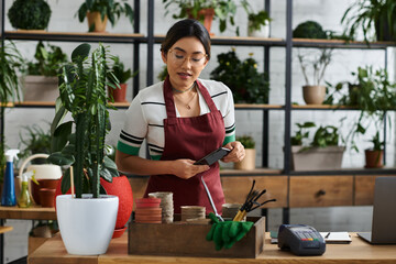 An Asian woman in an apron stands behind the counter of her plant shop © LIGHTFIELD STUDIOS