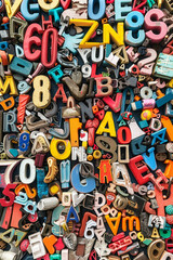 Naklejka premium A crowded assortment of fridge magnets in various shapes, sizes, and colors, filling the entire frame. The magnets include letters, numbers, and novelty designs.