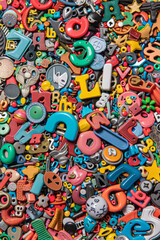 Fototapeta premium A crowded assortment of fridge magnets in various shapes, sizes, and colors, filling the entire frame. The magnets include letters, numbers, and novelty designs.