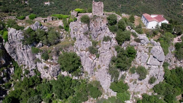 Aerial view of ancient ruins in rocky landscape with greenery, creating scenic backdrop. Castillo del Aguila, Gaucin pueblo, Malaga Spain