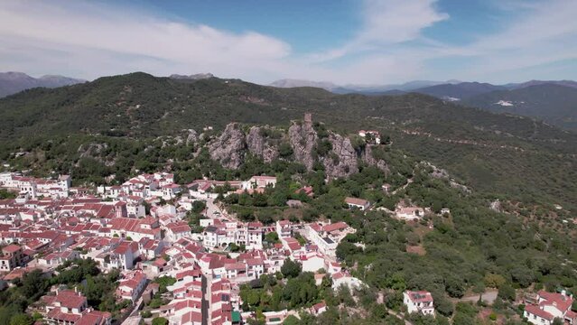 A medieval castle stands tall above a village nestled in the picturesque green mountains. Castillo del Aguila, Gaucin pueblo, Malaga Spain