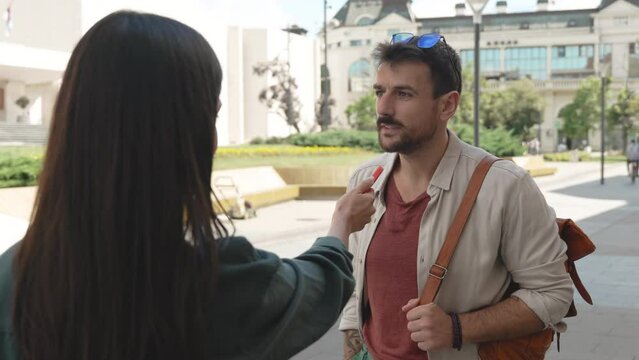 Young vlogger or journalist woman street interviewing freelancer expatriate or tourist male about life or business opportunities in the city. News reporter interview strangers about positive negative