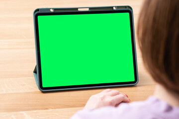 Young woman looking at her gadget with green screen