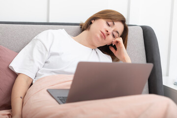 Attractive woman lying in the bed and working on laptop	