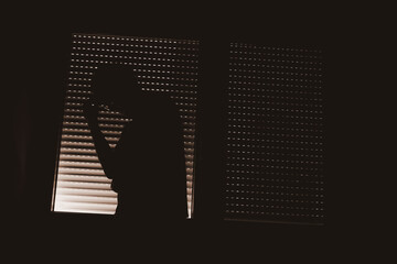 Paranoid personality disorder concept, silhouette of male person by the window with closed shutters