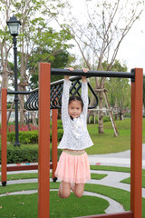 Fototapeta premium Portrait of Asian girl child enjoy to climbing aluminum fence in public park.