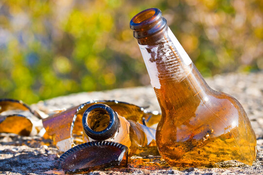 Shattered beer bottle resting on the ground: alcoholism concept - toned image