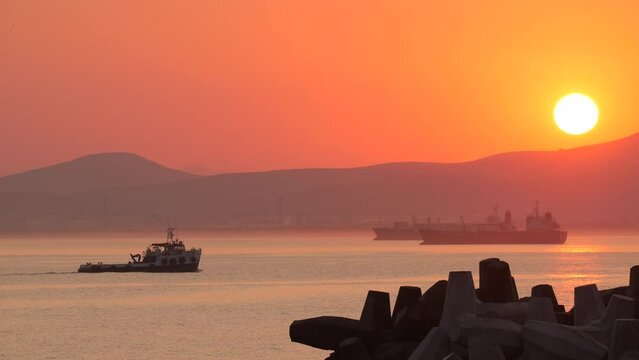 Shipping vessels approaching Cape Town port at dawn. Large container vessels in background, breakwater blocks in foreground. Audio retained for ambience in documentaries. Sea gulls audible.