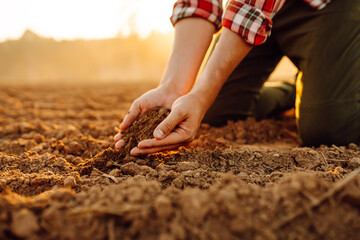Close up of the farmer hands touching dry ground in an agricultural field while analyzing soil during the summer day. Organic gardening, agriculture.