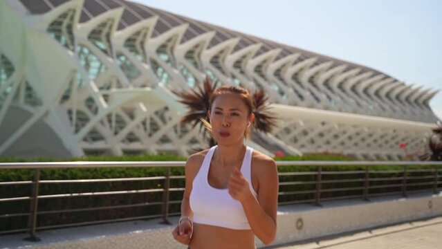 Asian oriental adult woman jogger in sportswear running workout lace up sunny morning urban high tech city background. Jogging training marathon, endurance result cardio exercise Healthy lifestyle