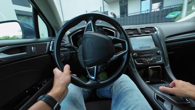 Male driver parks car in parking lot in courtyard of house, first point view. Man drives car, moves in reverse