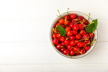 Cherries. Fresh ripe cherries with leaves on a textured wooden background. Fresh sweet organic cherry pile. Berries and fruits. Vegan. Healthy eating. Place for text. Copy space