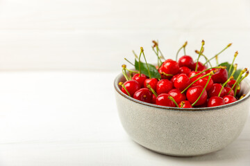 Cherries. Fresh ripe cherries with leaves on a textured wooden background. Fresh sweet organic cherry pile. Berries and fruits. Vegan. Healthy eating. Place for text. Copy space