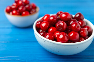 Cherries. Fresh ripe cherries with leaves on a textured wooden background. Fresh sweet organic cherry pile. Berries and fruits. Vegan. Healthy eating. Place for text. Copy space