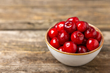 Cherries. Fresh ripe cherries with leaves on a textured wooden background. Fresh sweet organic cherry pile. Berries and fruits. Vegan. Healthy eating. Place for text. Copy space