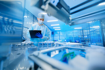 Pharmaceutical factory worker operating production line at pharmacy industry, man use clipboard for...