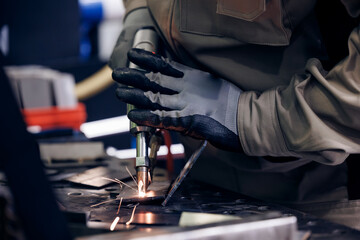 Worker use weld metal welding machine in workshop, blue sparks
