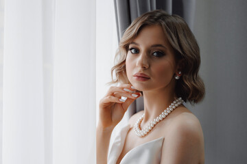 Portrait of happy elegant young woman in modern bridal look with classic hairstyle and makeup with...